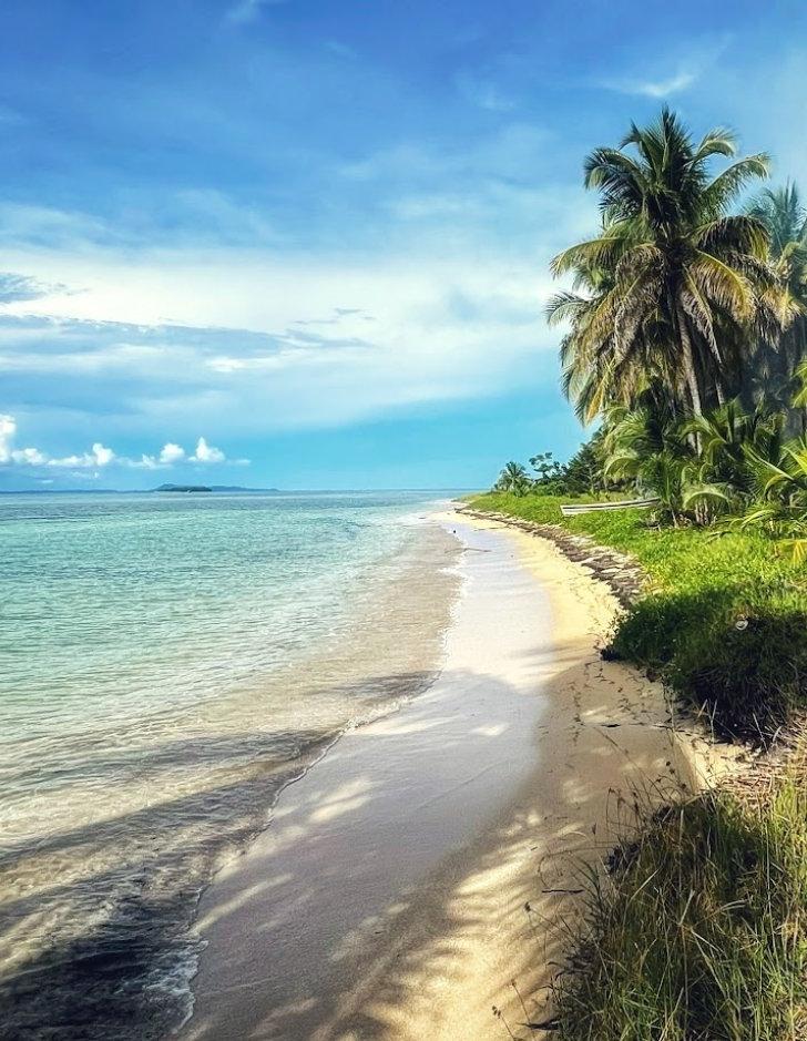 Photo of a white sandy beach and clear blue water